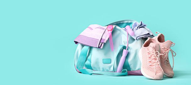 Bag with sportswear and equipment on light blue background - Фото, изображение