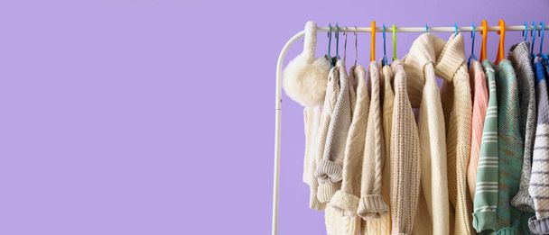 Rack with children sweaters near lilac wall in room - Photo, Image