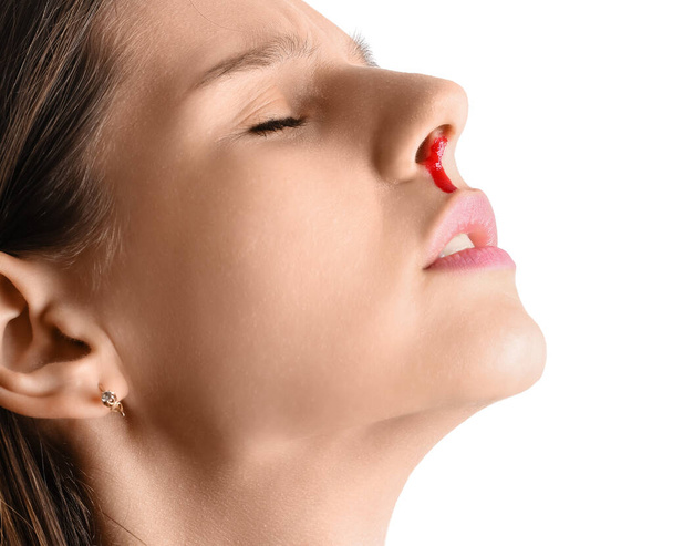 Mujer joven con hemorragia nasal sobre fondo blanco, primer plano - Foto, Imagen
