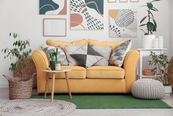 Interieur eines stilvollen Wohnzimmers mit Zimmerpflanzen, gelbem Sofa und Rahmen - Foto, Bild