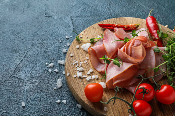 Wooden board with slices of tasty ham, vegetables and microgreen on dark color background - Fotografie, Obrázek