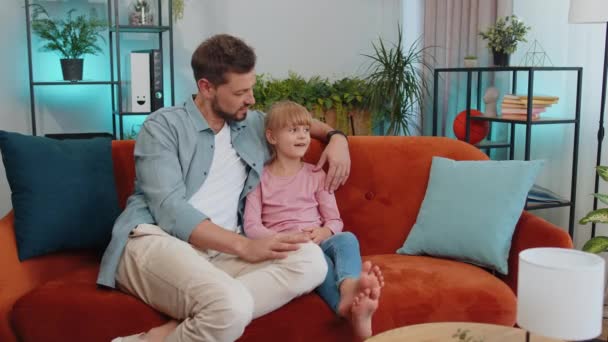 Young loving man dad talking to little 7s daughter toddler together on couch at home. Preschool kid and father having warm trustworthy conversation, good relation. Understanding, family bond concept - Metraje, vídeo