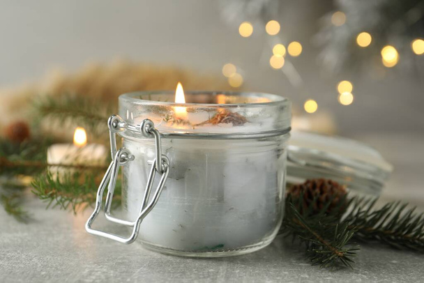 Burning scented conifer candle and Christmas decor on grey table - Fotoğraf, Görsel