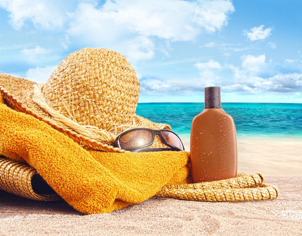 zonnebrand lotion, stro hoed op het strand - Foto, afbeelding
