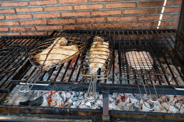 Świeże ryby grillujące na starych parrillach węgla drzewnego białe ryby okoń morski i skarpa, zbudowany na zewnątrz budynków w małej wiosce rybackiej Getaria, Kraj Basków, Hiszpania - Zdjęcie, obraz