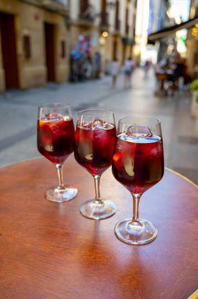 Glazen koude sangria wijn geserveerd buiten in bar met uitzicht op de oude straat in San Sebastian, Baskenland, Spanje in de zomer - Foto, afbeelding