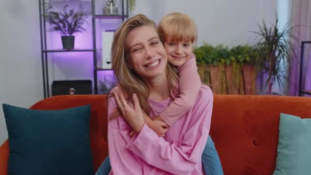 Pretty smiling cute child kid daughter embrace mom look at camera. Happy beautiful family young adult single mother foster nanny parent and toddler girl hug enjoy sweet tender love. Close-up portrait - Filmati, video