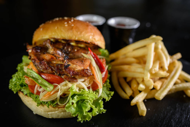 vynikající grilované kuřecí burger a hranolky na černém dřevěném stole pozadí - Fotografie, Obrázek