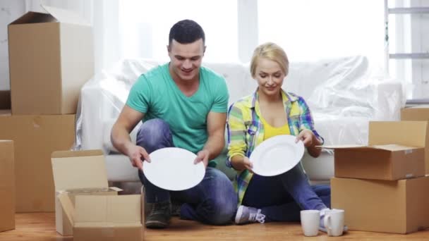 uśmiechnięta para rozpakowaniu pudełka z naczyniami - Materiał filmowy, wideo