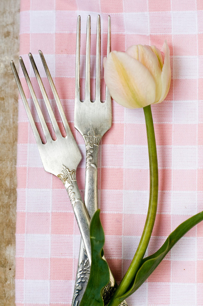 Os dois garfos de sobremesa estão perto de tulipa em uma toalha de mesa
 - Foto, Imagem
