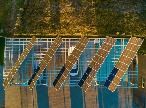 Вид с воздуха над инновационными солнечными панелями, расположенными на автостоянке, много крыш делает хорошее использование небольшого пространства в городе для зарядки электромобилей. - Фото, изображение