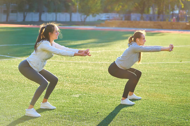 Két gyönyörű sport gyakorlása együtt a gyep, a kora reggeli órákban lányok. - Fotó, kép