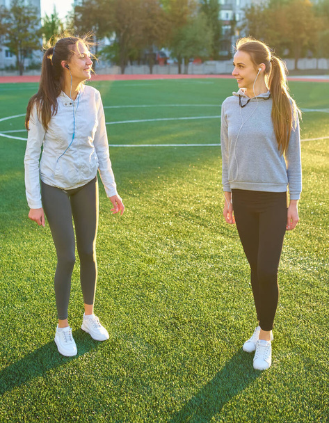 Deux belles filles sportives s'exerçant ensemble sur une pelouse tôt le matin
. - Photo, image