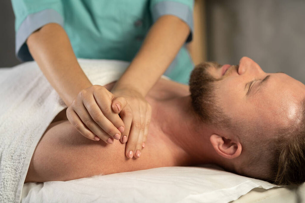 Imagen recortada de terapeuta masajeando pecho y hombros de paciente masculino en consultorio médico. Copiar espacio - Foto, Imagen