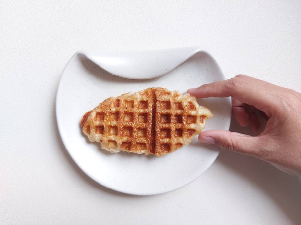 Croffle or croissant waffle on white plate. Viral dessert or snack. Sweet taste. Usually served with any topping. Delicious. Soft inside crunchy outside. Isolated background in white. Copy space. - Foto, imagen