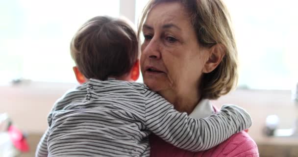 Abuela sosteniendo al nieto bebé en brazos consolando al niño - Metraje, vídeo