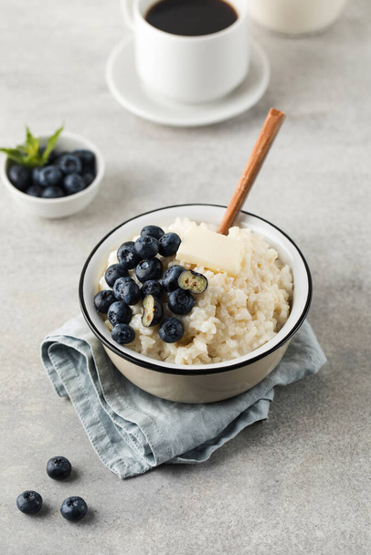 Rice milk porridge with blueberries and a mug of black coffee. The concept of a healthy and tasty breakfast. - Valokuva, kuva