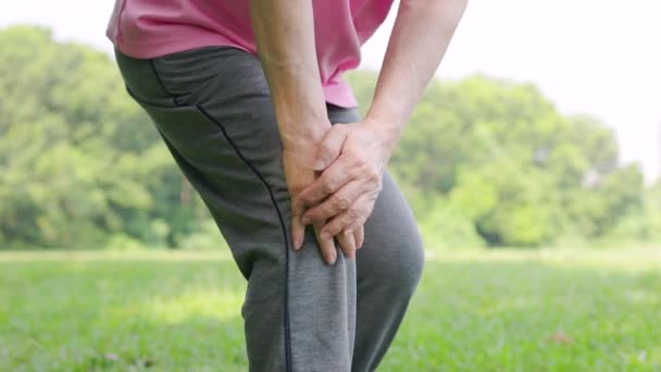 Ηλικιωμένη γυναίκα που αισθάνεται πόνο στο γόνατο κατά την άσκηση στο πάρκο - Πλάνα, βίντεο