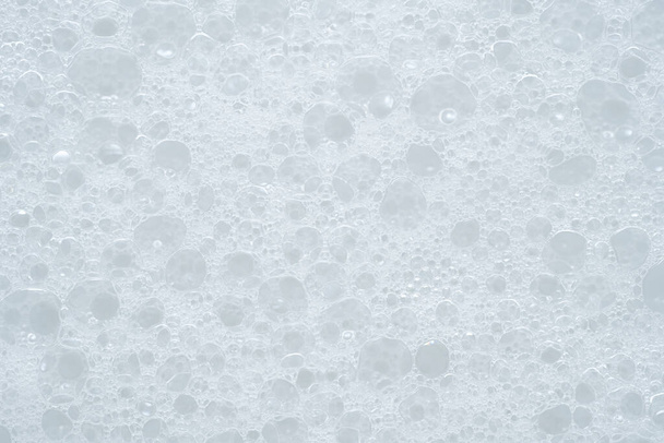 White foam texture. Soapy liquid. Skin care cleansing cosmetic in top view. Cleanser or shampoo with bubbles - Photo, Image