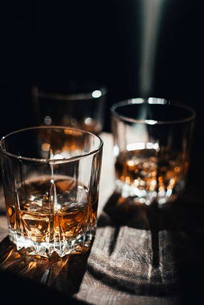 Whiskey with ice in glasses, rustic wood background, copy space - Photo, Image