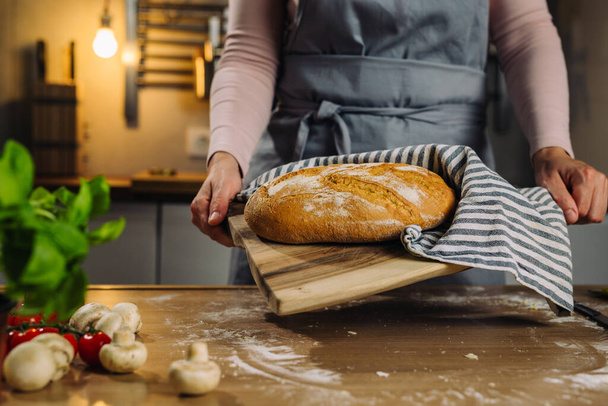 close up of woman holding fresh homemade bread in home kitchen - Photo, Image
