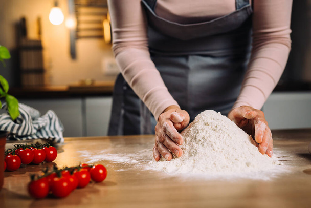 woman prepares dough in home kitchen - Foto, afbeelding
