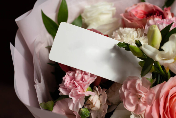 bouquet de fleurs et une carte de l'expéditeur. admirateur inconnu. Roses, œillets, lisianthus. maquette de carte - Photo, image