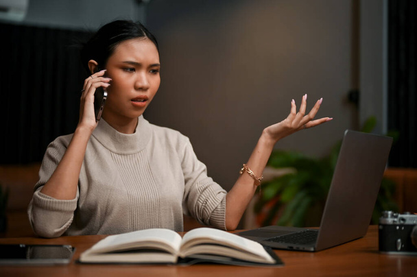 Femme d'affaires asiatique professionnelle ou patronne au téléphone avec son équipe, résoudre des problèmes au téléphone, travailler tard dans la nuit au bureau. - Photo, image