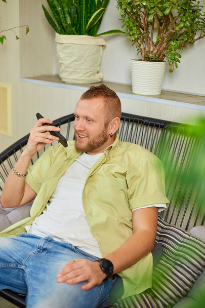 Happy hymyilevä mies tilalla matkapuhelin puhuu ystävien tai perheen kanssa käyttäen kaiutin, uuden teknologian käsite. Positiivinen mies nauttia keskustelun ystävän kanssa älypuhelimen kautta. - Valokuva, kuva