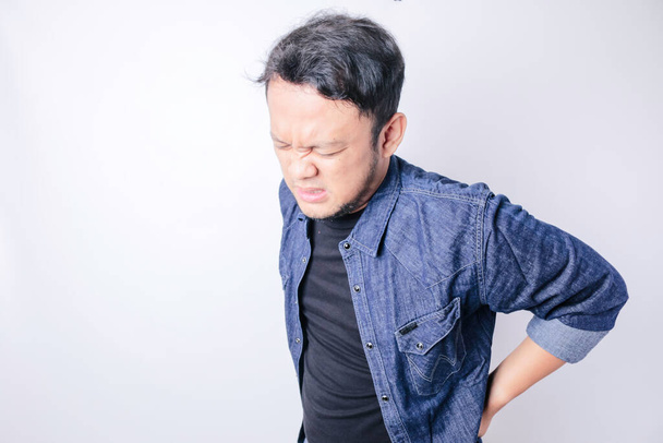 Asian handsome man suffering from backache for having made an effort over isolated white background - Fotó, kép