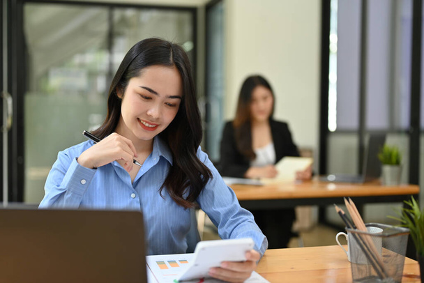 Attraktive und schöne junge asiatische Geschäftsfrau oder Buchhalterin bei der Arbeit an ihrem Schreibtisch im Co-Working Room. - Foto, Bild