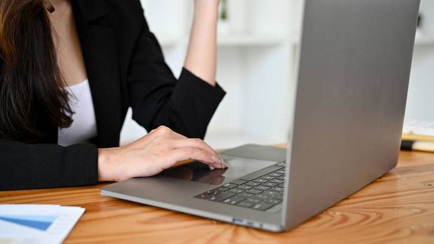 Profesjonalna azjatycka bizneswoman w czarnym garniturze pracuje nad projektem na laptopie w biurze. strzał odcięty - Zdjęcie, obraz