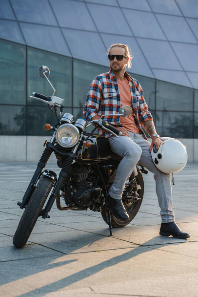 Portrait of bearded macho biker with sunglasses and old fashioned motorcyle. - Foto, Bild
