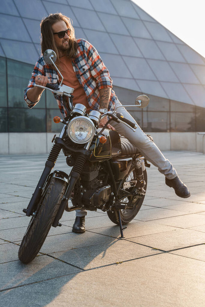 Stílusos férfi motoros szakállal és napszemüveggel motorozik.. - Fotó, kép