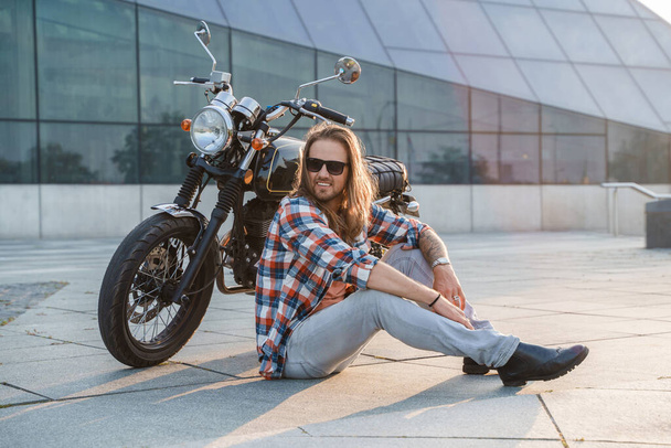Muotokuva cool kaveri biker aurinkolasit istuu asfaltti. - Valokuva, kuva