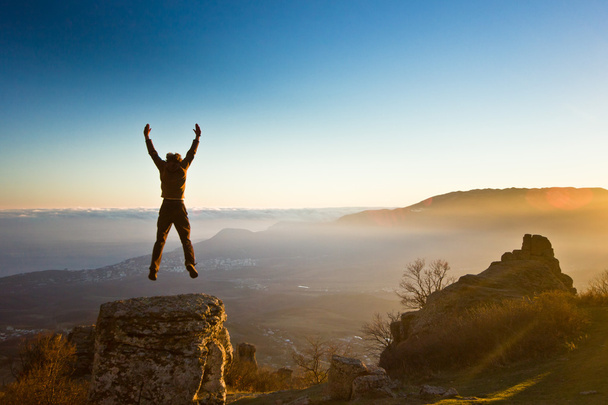man with hands up in the mountains against sun - Fotó, kép