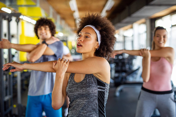 Group of sportive fit people working out in a gym. Multiracial friends exercising together in fitness club. - Foto, Imagen