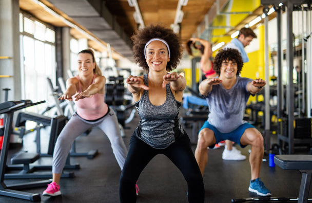 Multiethnic group of people training in a gym. Trainer and sportive fit persons exercising in a fitness class - Fotografie, Obrázek