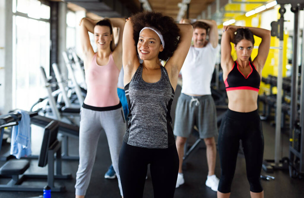 Fitness, sport, people and lifestyle concept. Group of smiling people exercising together in gym or studio - Фото, изображение