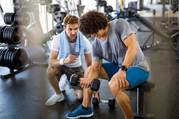 Fit young man working out in gym with personal trainer to stay healthy. Sport, people concept - Photo, image