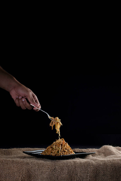男はフォークで麺を選ぶ,黒の背景,中国料理  - 写真・画像