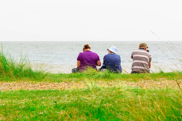 Suffolk, İngiltere - 7 Eylül 2022 - Minsmere plajında oturan bir ailenin arka görüntüsü - Fotoğraf, Görsel