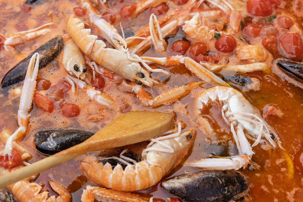 Vaření italských špaget allo scoglio, těstoviny s mořskými plody a rajčaty na pánvi. Středomořské apulijské tradiční jídlo s čerstvými dušenými škeblemi, krevetami, mušlemi, chobotnicemi a olihněmi - Fotografie, Obrázek