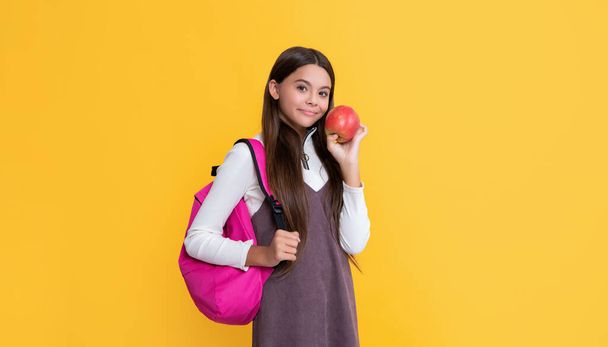 child smile with school backpack and apple on yellow background. - Photo, Image