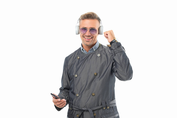 Gelukkige man die luistert naar muziek die een winnend gebaar maakt. Muziekspeler in smartphone. Mobiele muziek. - Foto, afbeelding