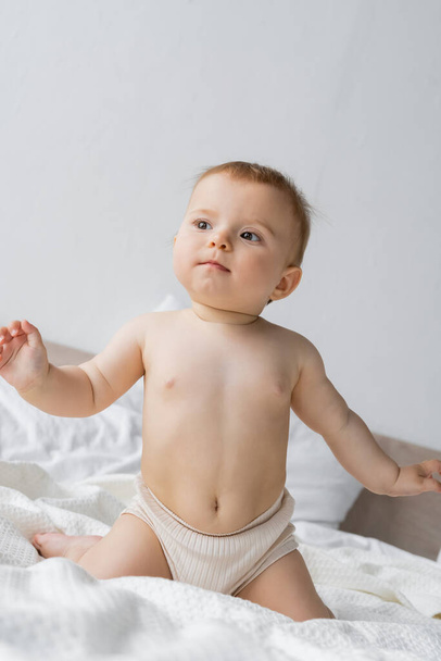 Infant girl in panties sitting on bed in morning  - Photo, Image