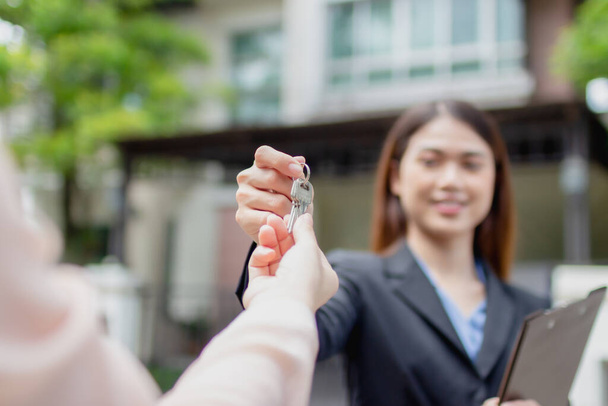 Young asian woman holding the key with new house. Real Estate Agent giving house keys - Photo, Image