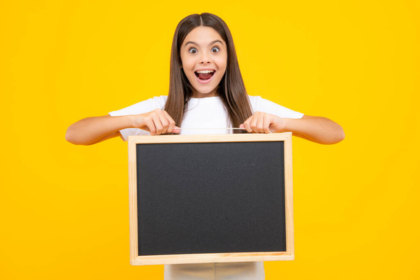 Dospívající školačka drží tabuli. Dětská reklama. Zpátky do školy. Nadšený teenager, rád ohromený a nadšený emoce - Fotografie, Obrázek