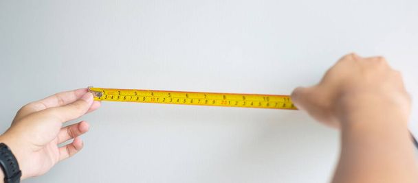 Man hand using tape measure for measuring with wall backgrounds at home. DIY, Interior design, repairing and improvement home or apartment concepts - Fotoğraf, Görsel