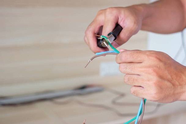 Elektrikçi penseyle elektrik kablolarını kesiyor, prizlerin elektrik kablolarını yerleştiriyor. Tamir, yenileme, onarım, hizmet ve konut kavramlarının geliştirilmesi - Fotoğraf, Görsel